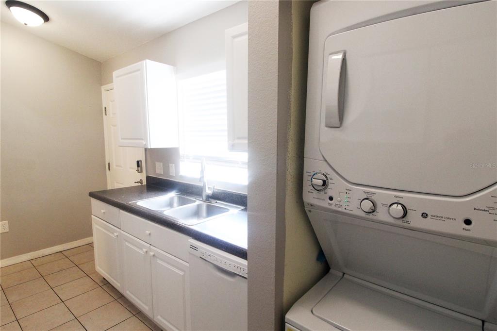 A kitchen with white cabinets, a double sink, and a stacked washer-dryer unit — 864 HAND AVE, SARASOTA, FL