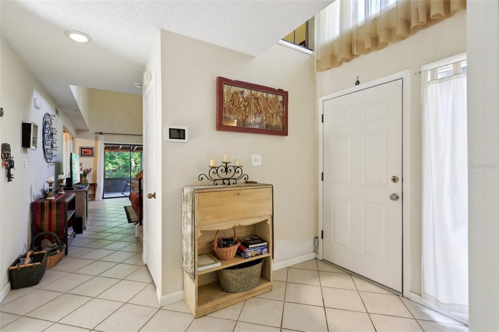 An entryway features tiled floors, a wooden cabinet, a white door, and a view into a living area — 4836 PEBBLE BEACH DRIVE, ORLANDO, FL