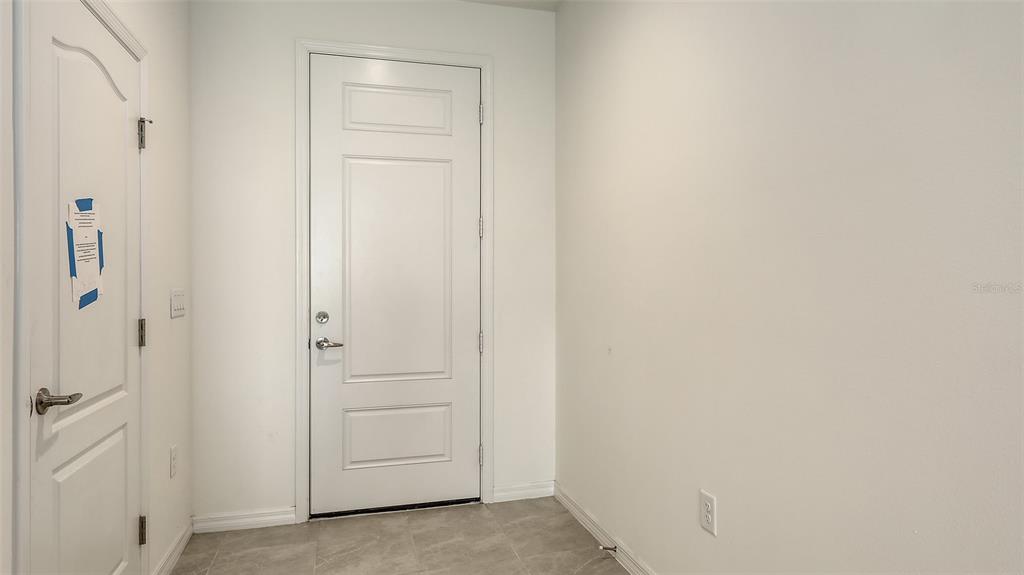 A white door and a door with blue tape stand in a room with tile flooring — 2360 WASHINGTON PALM COURT, BRADENTON, FL