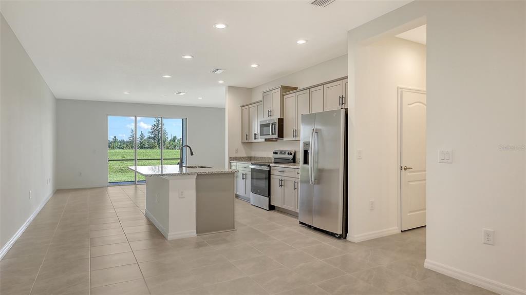 A kitchen with light gray cabinets, stainless steel appliances, and an island overlooks a backyard — 2360 WASHINGTON PALM COURT, BRADENTON, FL