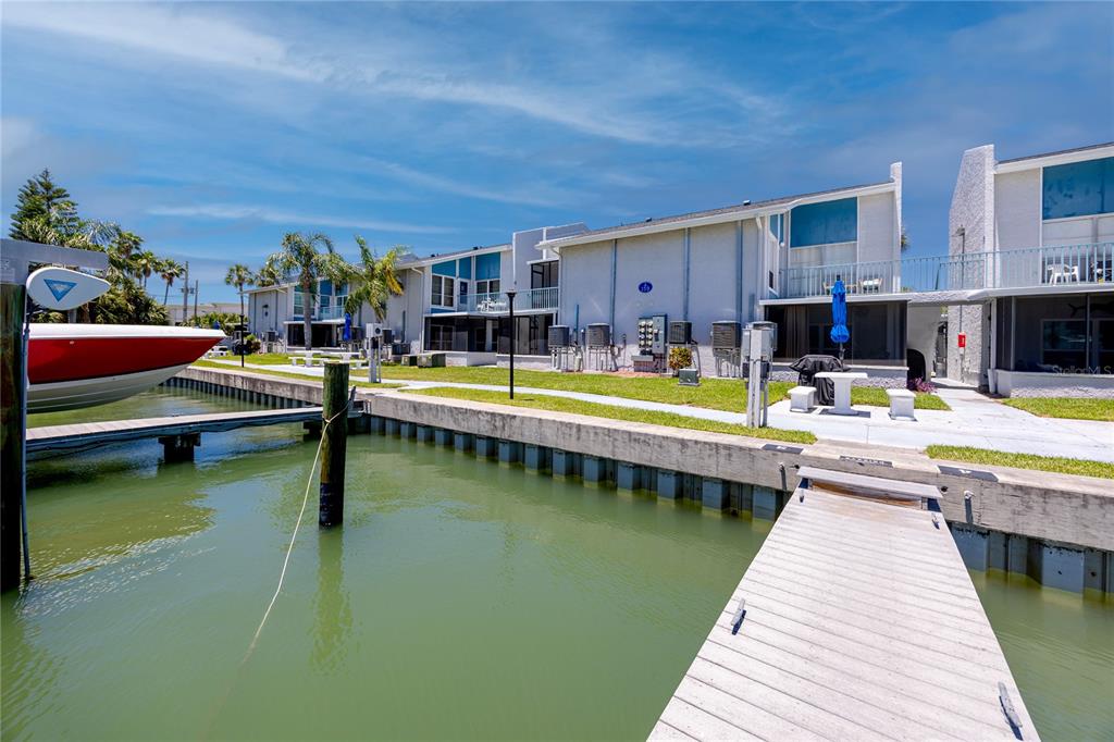 A view of a waterfront condo complex with a boat dock and green lawn — 159 MEDALLION BOULEVARD UNIT F, MADEIRA BEACH, FL
