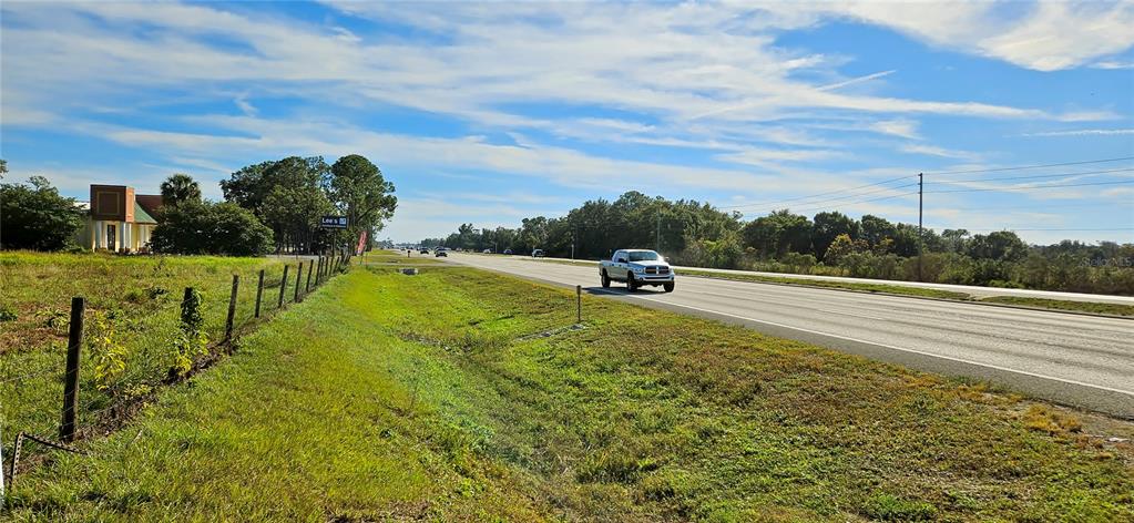 A white pickup truck drives along a highway next to a grassy field and trees — US-27, LAKE WALES, FL