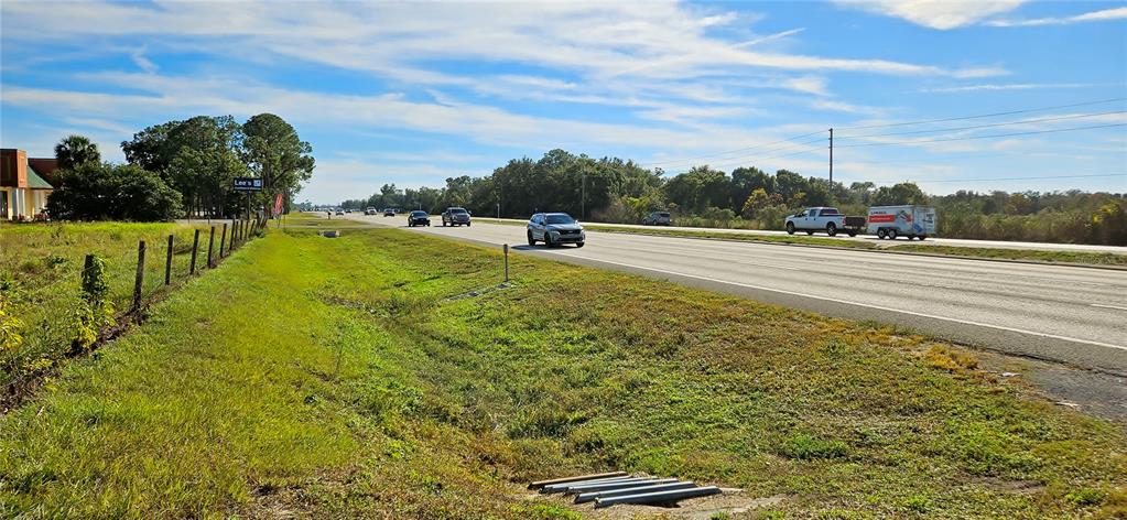 A view of a highway with a grassy shoulder and a fence on the left — US-27, LAKE WALES, FL