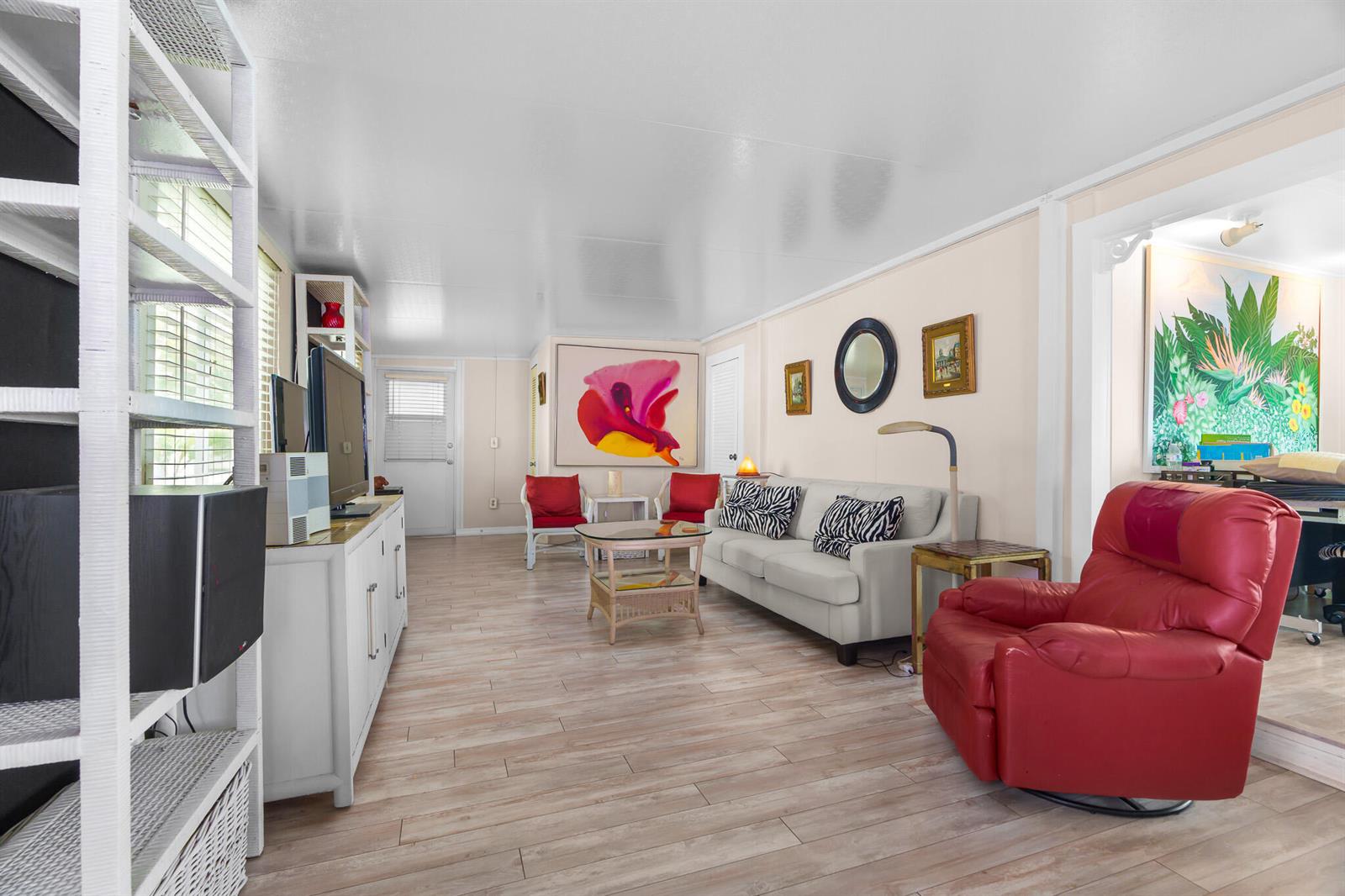 A living room features a white sofa, a red recliner, and light wood-look flooring — 202 N Ibis, Briny Breezes FL 33435, BRINY BREEZES, FL