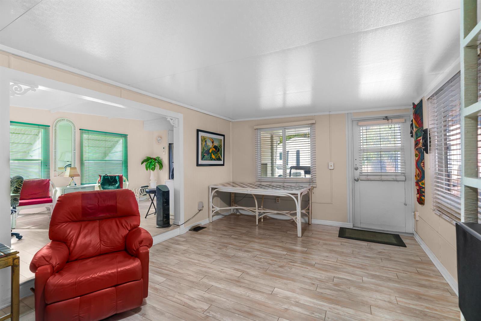 A living room with light wood-look flooring, a red recliner, and a white rattan table — 202 N Ibis, Briny Breezes FL 33435, BRINY BREEZES, FL