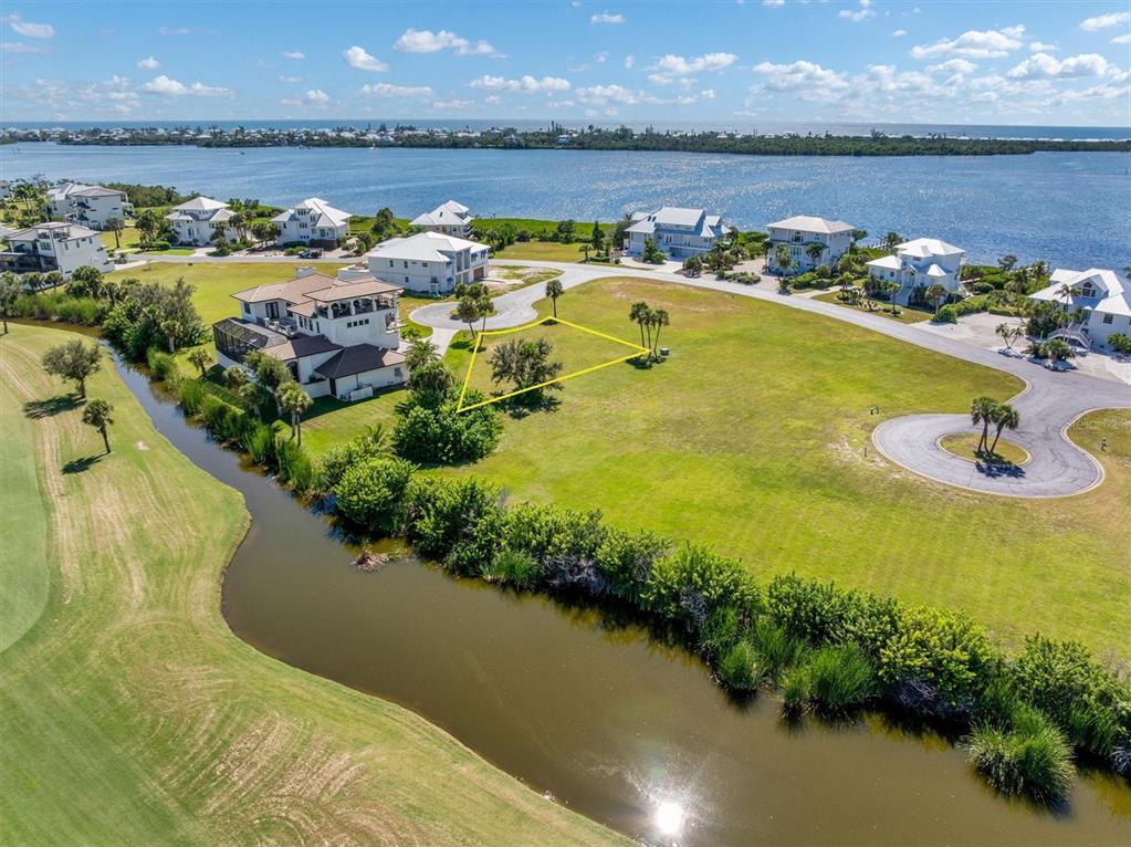 An aerial view shows a vacant residential lot outlined in yellow near a waterfront community — 9310 TALON COURT, ENGLEWOOD, FL