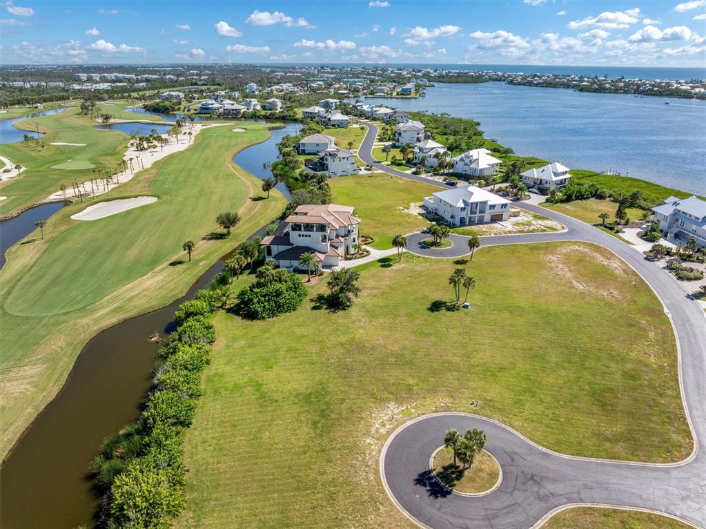 An aerial view shows houses situated between a golf course and a large body of water — 9310 TALON COURT, ENGLEWOOD, FL