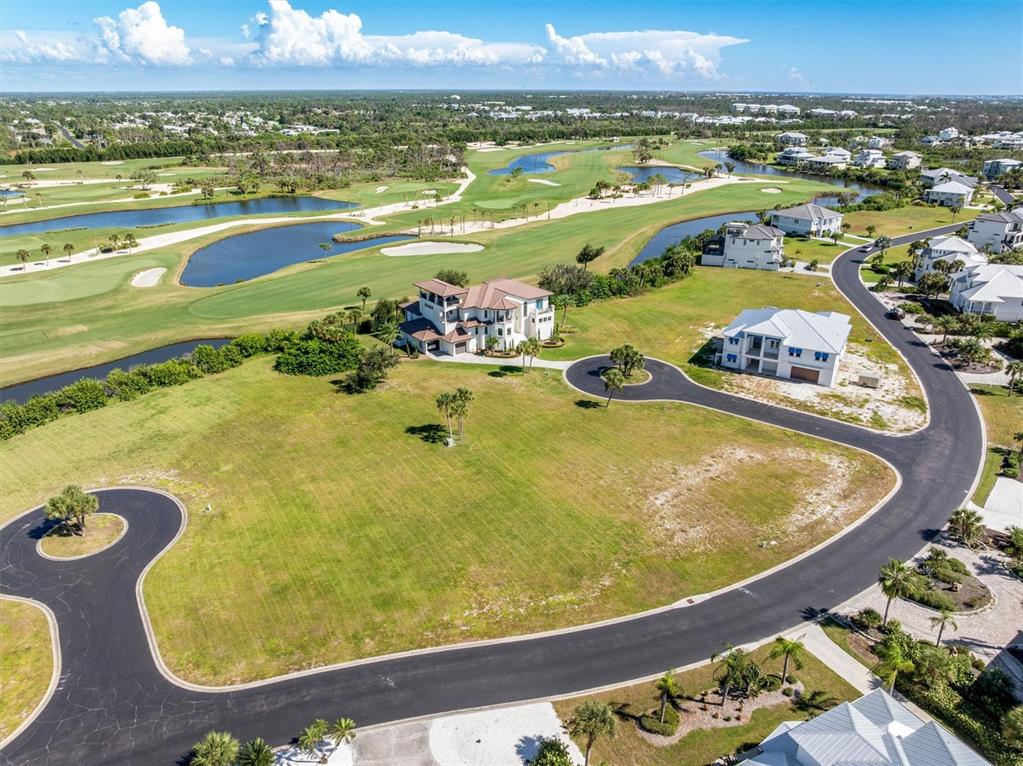 An aerial view shows a large house and a vacant lot beside a golf course — 9310 TALON COURT, ENGLEWOOD, FL