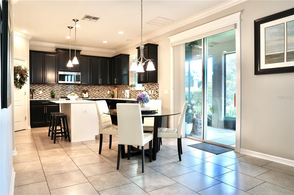 A screened-in porch features tiled flooring, a small bistro table, and a view of trees — 15665 CITRUS HARVEST ROAD, WINTER GARDEN, FL