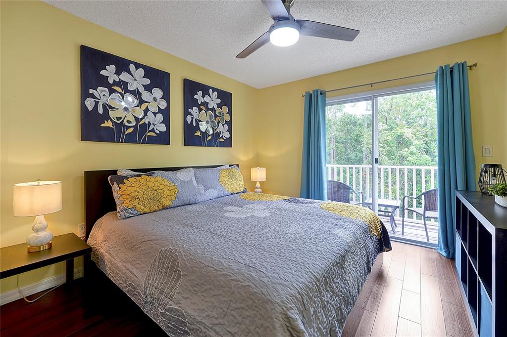 A bedroom features a bed with floral bedding, yellow walls, and a sliding glass door — 2767 SUN KEY PLACE, KISSIMMEE, FL
