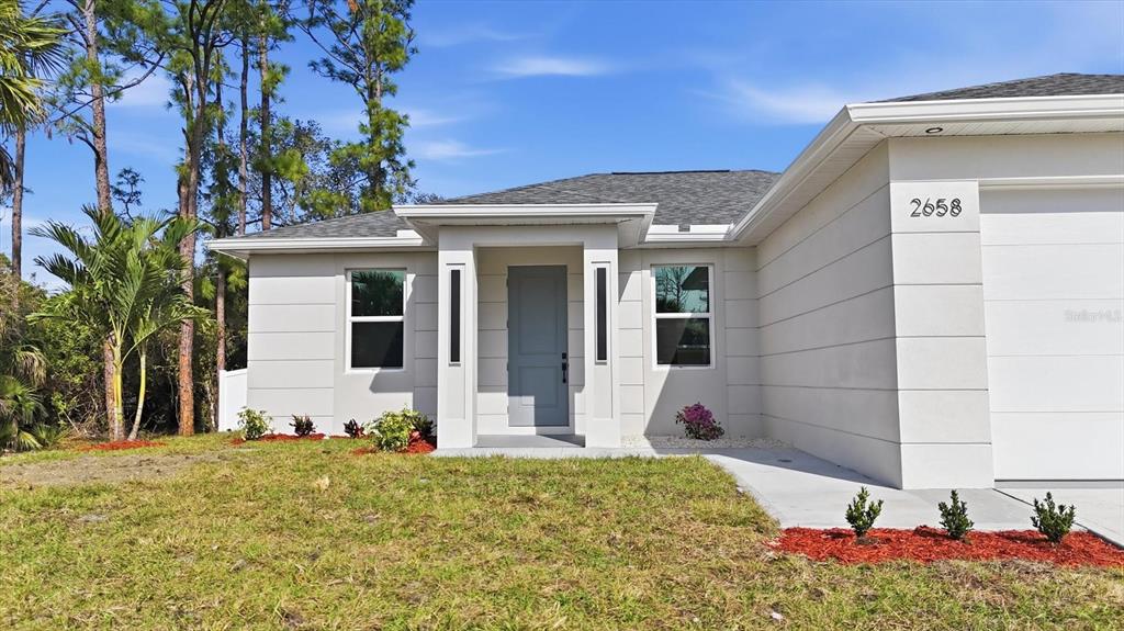 A modern, single-story house exterior features white paneled walls, a gray door, and a garage — 2658 ALLSUP TERRACE, NORTH PORT, FL