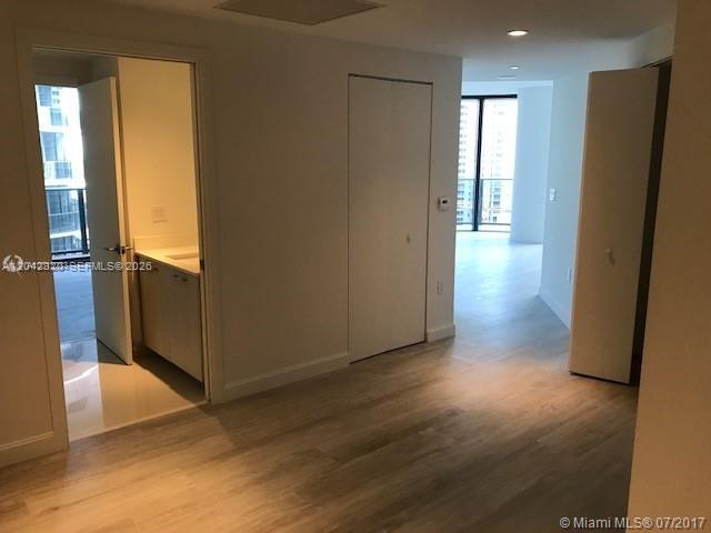 An interior view shows a hallway with light wood floors, closet doors, and a bathroom entrance — 55 SW 9th St # 2103, Miami FL 33130, MIAMI, FL