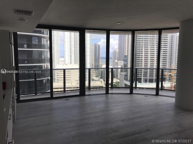 An empty room with light wood floors and floor-to-ceiling windows overlooking a city skyline — 55 SW 9th St # 2103, Miami FL 33130, MIAMI, FL