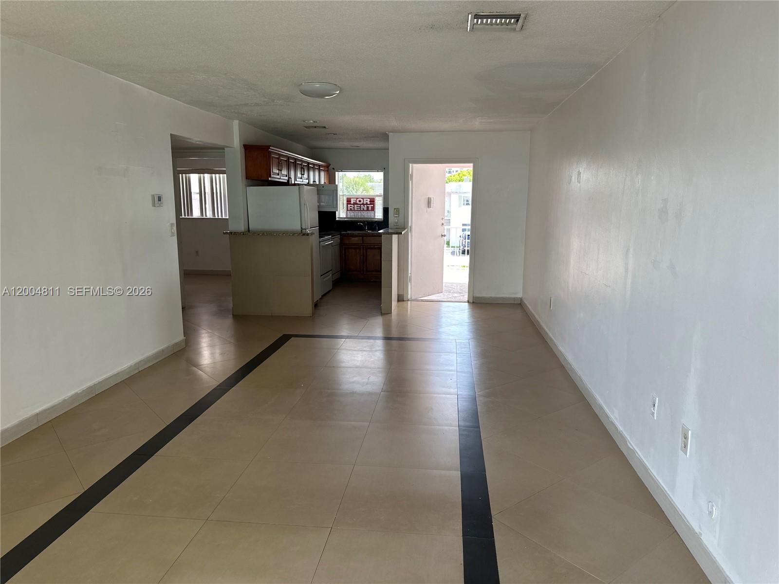 An open-concept living area features tile flooring and a kitchen with wooden cabinets — 7424 SW 82nd St # D216, Miami FL 33143, MIAMI, FL