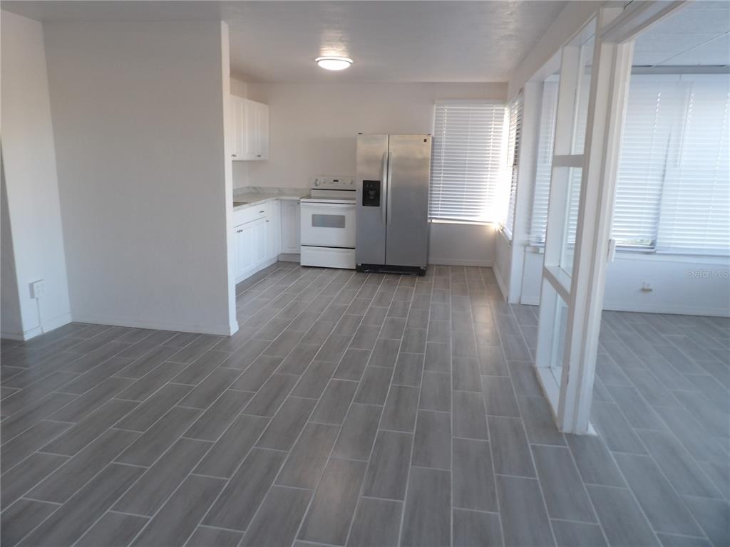 A kitchen with white cabinets, a stainless steel refrigerator, and gray wood-look tile flooring — 14975 1ST STREET E, MADEIRA BEACH, FL