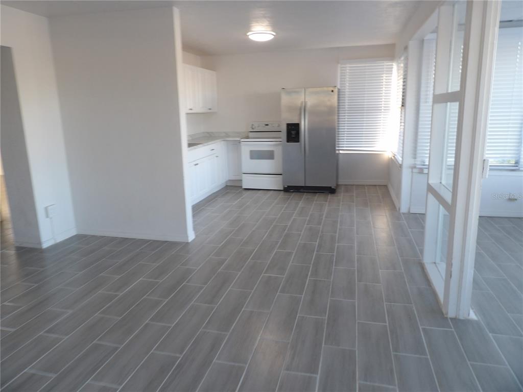 A kitchen with white cabinets, a white stove, and a stainless steel refrigerator on gray flooring — 14975 1ST STREET E, MADEIRA BEACH, FL