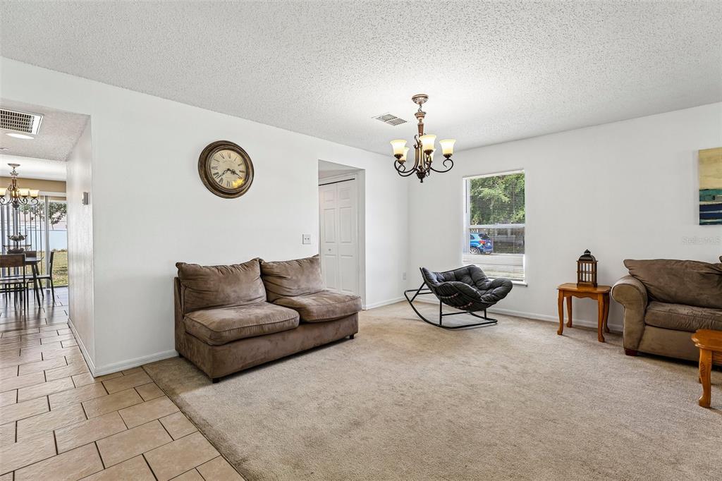 A living room with beige carpet, two brown sofas, a rocking chair, and a chandelier — 274 JOCELYN DRIVE, DAVENPORT, FL