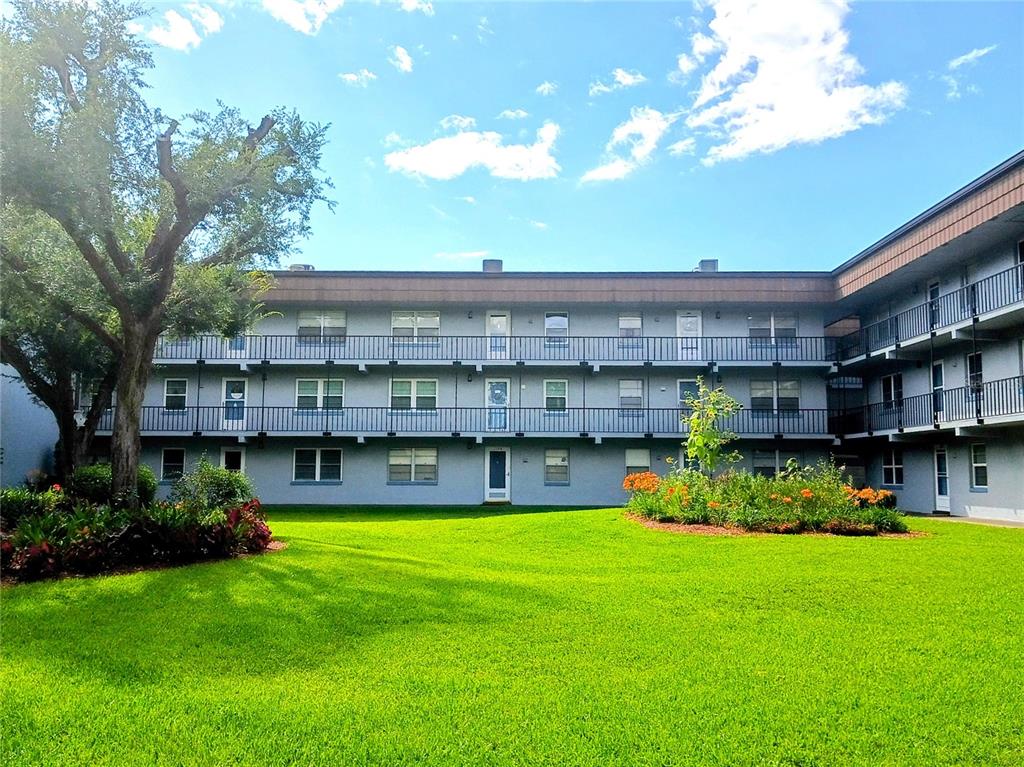 A three-story apartment building with exterior walkways and a lawn in the foreground — 333 LAKE HOWARD DRIVE NW UNIT 312C, WINTER HAVEN, FL