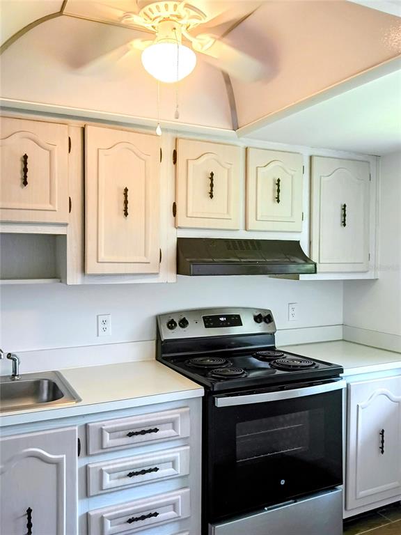 A kitchen features light-colored cabinets, a black stove, and a ceiling fan — 333 LAKE HOWARD DRIVE NW UNIT 312C, WINTER HAVEN, FL