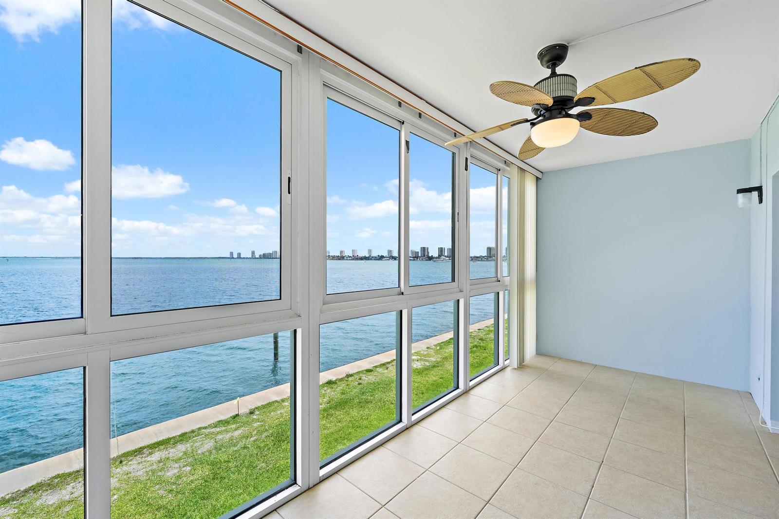 A sunroom with tile flooring, a ceiling fan, and large windows overlooking the water — 400 Wilma Circle # 206, Riviera Beach FL 33404, RIVIERA BEACH, FL