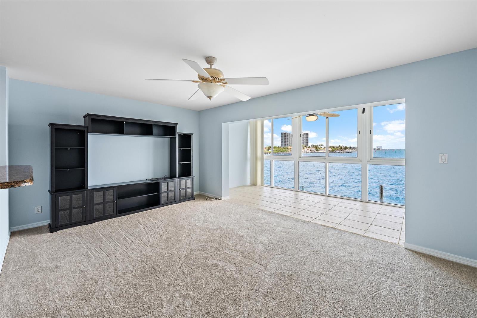 A living room with carpet, a large entertainment center, and floor-to-ceiling windows overlooking the water — 400 Wilma Circle # 206, Riviera Beach FL 33404, RIVIERA BEACH, FL