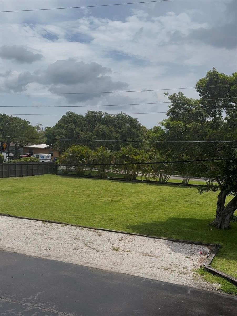 A grassy lot features a gravel driveway, a wooden fence, and several palm trees — 610 NW 7th Avenue, Pompano Beach FL 33060, POMPANO BEACH, FL