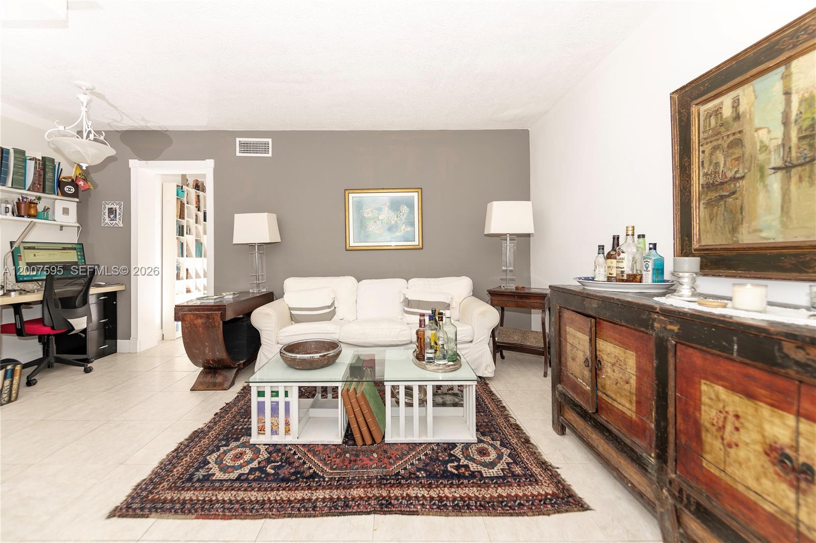 A living room features a white sofa, a patterned rug, and a rustic wooden sideboard — MIAMI BEACH, FL