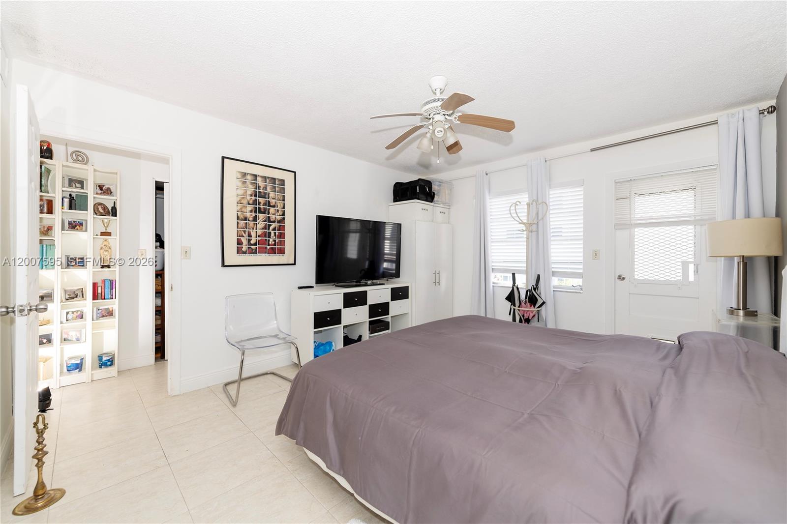A bedroom features a bed, a television on a storage unit, and a tall bookshelf — MIAMI BEACH, FL