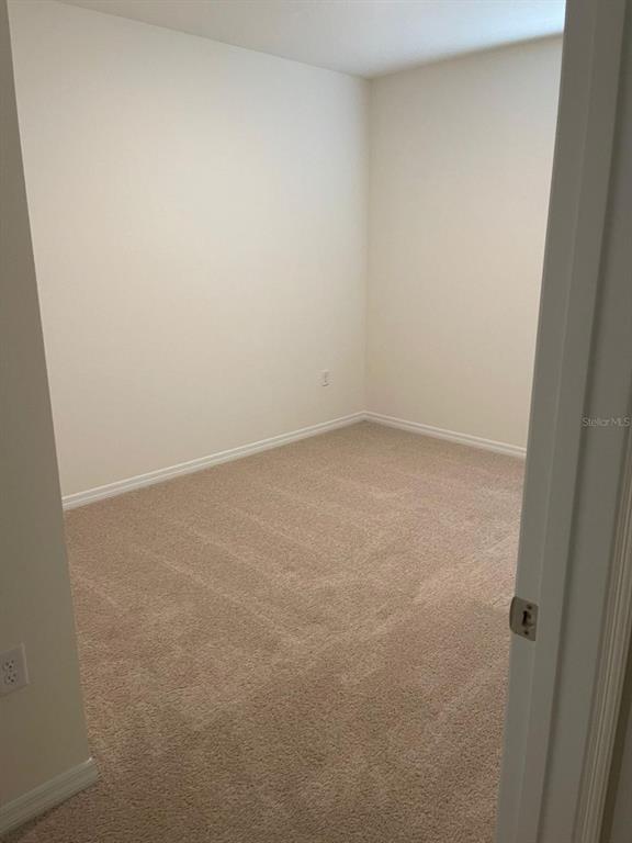 An empty room with beige carpet and plain off-white walls viewed through a doorway — 927 WATERFALL BOULEVARD, DAVENPORT, FL
