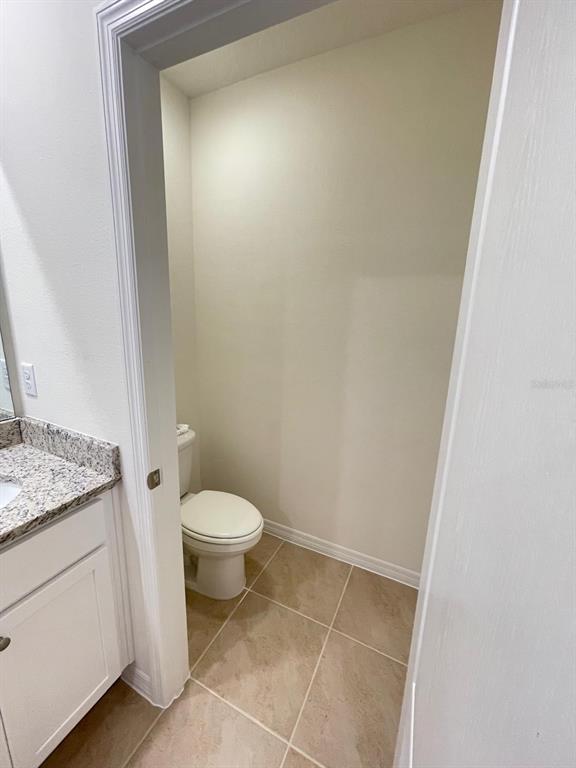 A small, enclosed toilet room with beige tile flooring and white walls — 927 WATERFALL BOULEVARD, DAVENPORT, FL