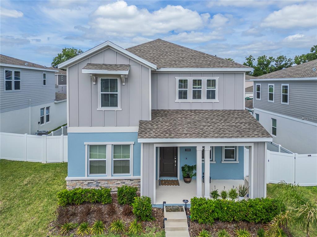 A two-story house with blue and gray siding, a front porch, and stone accents — 2200 SWEET HONEY LANE, APOPKA, FL