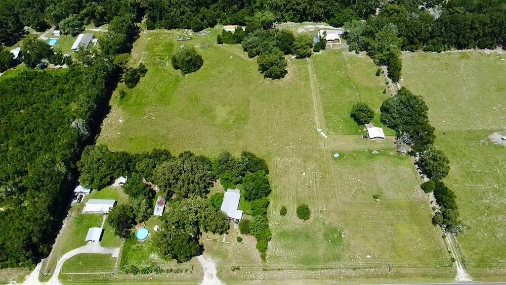 An aerial view shows a rural property with multiple buildings, a pool, and large pastures — 15770 NW 60TH AVENUE, CHIEFLAND, FL