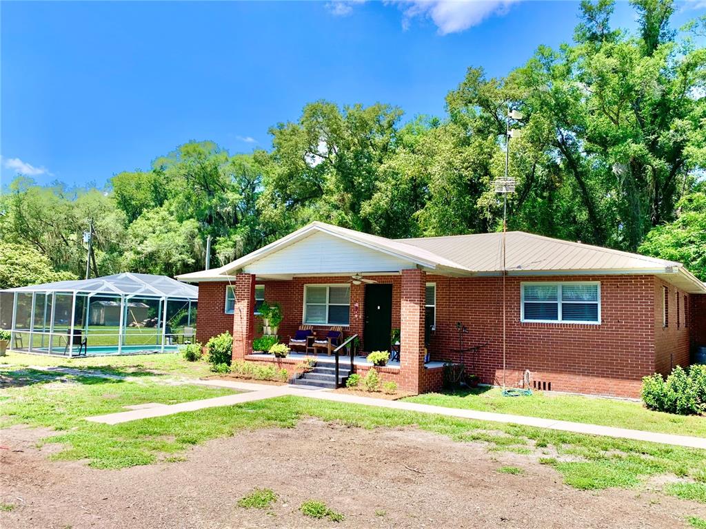 A single-story brick house with a front porch and an adjacent screened-in pool enclosure — 15770 NW 60TH AVENUE, CHIEFLAND, FL