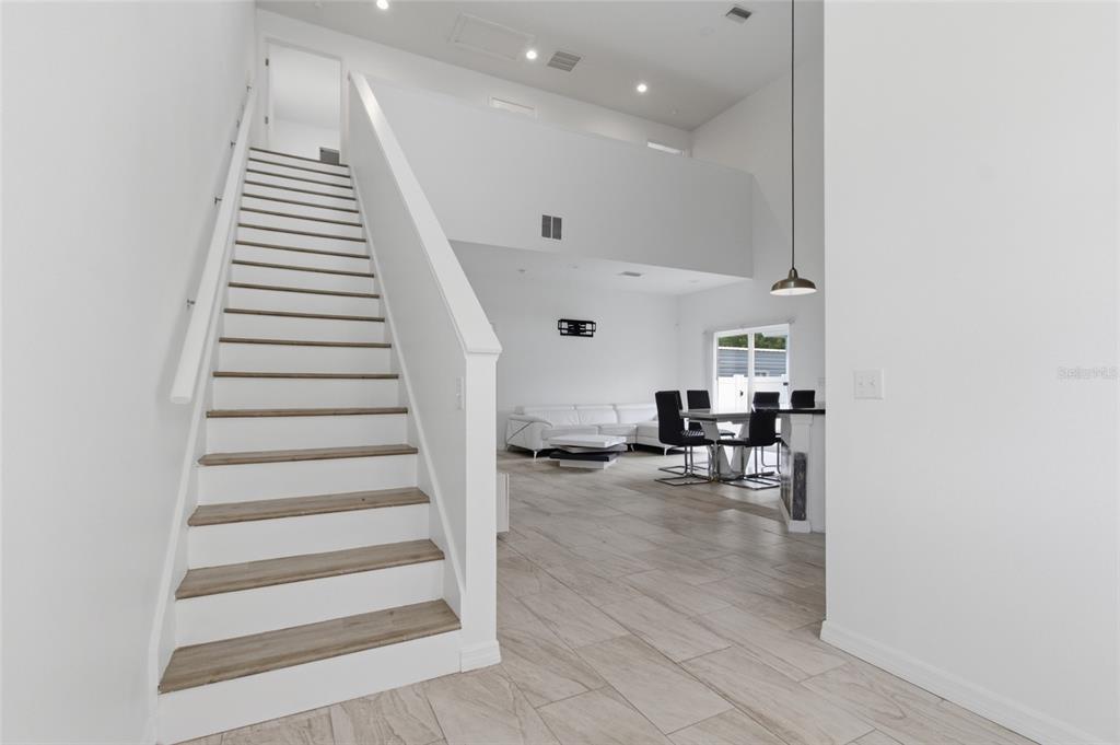 A staircase with wood treads leads to an upper level overlooking an open-concept living area — 3702 WIGGINS LEAF STREET, TAMPA, FL