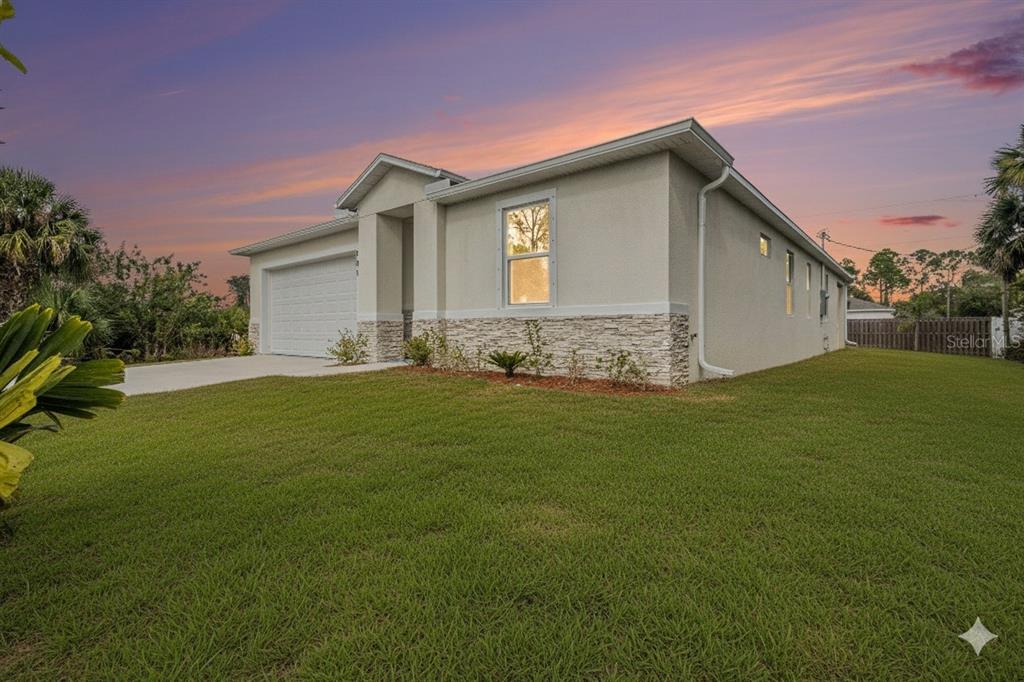 A single-story house with a white garage, stone veneer siding, and a grassy front yard — 801 GELASO STREET SW, PALM BAY, FL