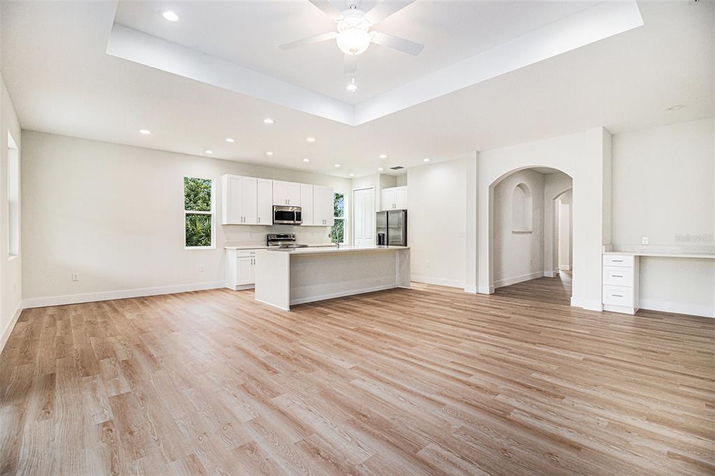 A spacious open-concept kitchen and living area with light wood flooring and a tray ceiling — 801 GELASO STREET SW, PALM BAY, FL