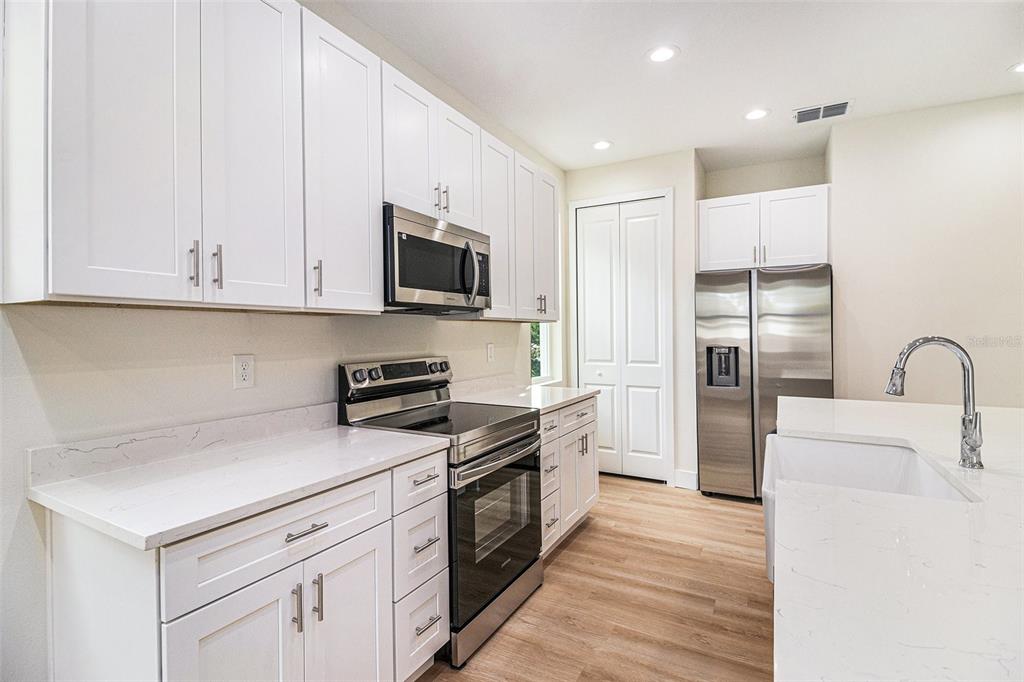 A modern kitchen features white cabinets, stainless steel appliances, and a white quartz island — 801 GELASO STREET SW, PALM BAY, FL