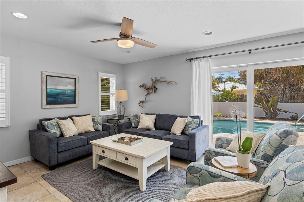 A living room features two blue sofas, a white coffee table, and a pool view — 110 PALM AVENUE, ANNA MARIA, FL