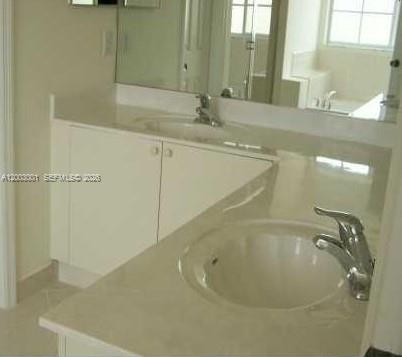 A bathroom vanity with a white cabinet, light-colored countertop, and two sinks with chrome faucets — 1955 NE 36th Ave # 0, Homestead FL 33033, HOMESTEAD, FL