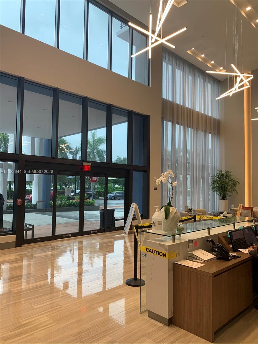 A modern lobby features a reception desk, floor-to-ceiling windows, and geometric pendant lighting — 5350 NW 84 Ave # 1601, Doral FL 33166, DORAL, FL