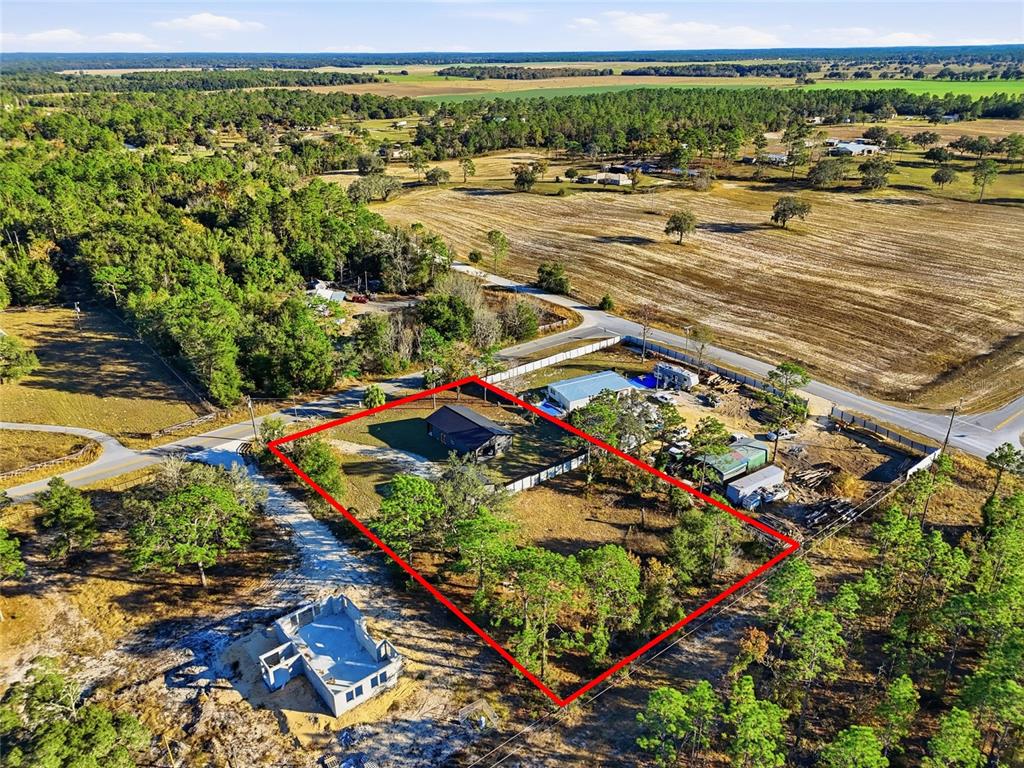An aerial view shows a house on a fenced lot with a nearby unfinished structure — 4030 NE 140TH COURT, WILLISTON, FL