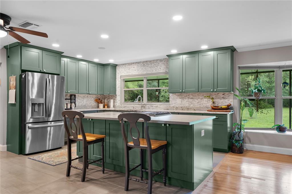 A living room with hardwood floors, a large patterned rug, and an open-concept kitchen — 19226 SE 24TH AVENUE, HAWTHORNE, FL