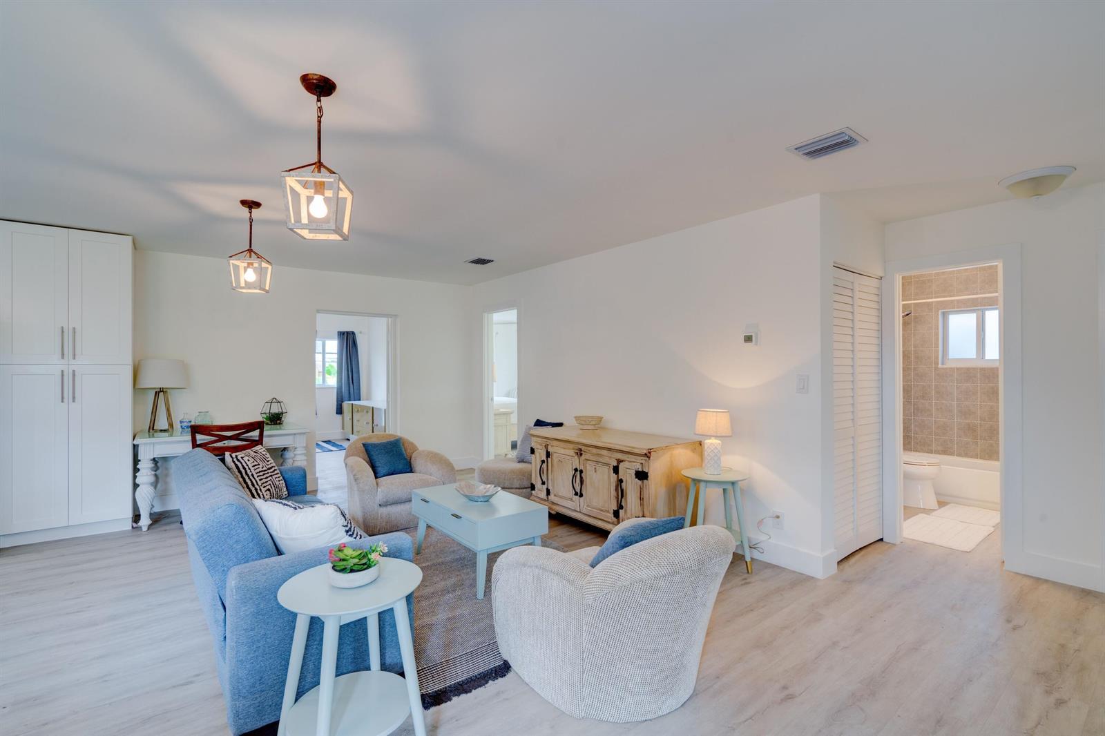 A bright living room features light wood flooring, a blue sofa, and two armchairs — 1036 Coral Drive, Boynton Beach FL 33426, BOYNTON BEACH, FL