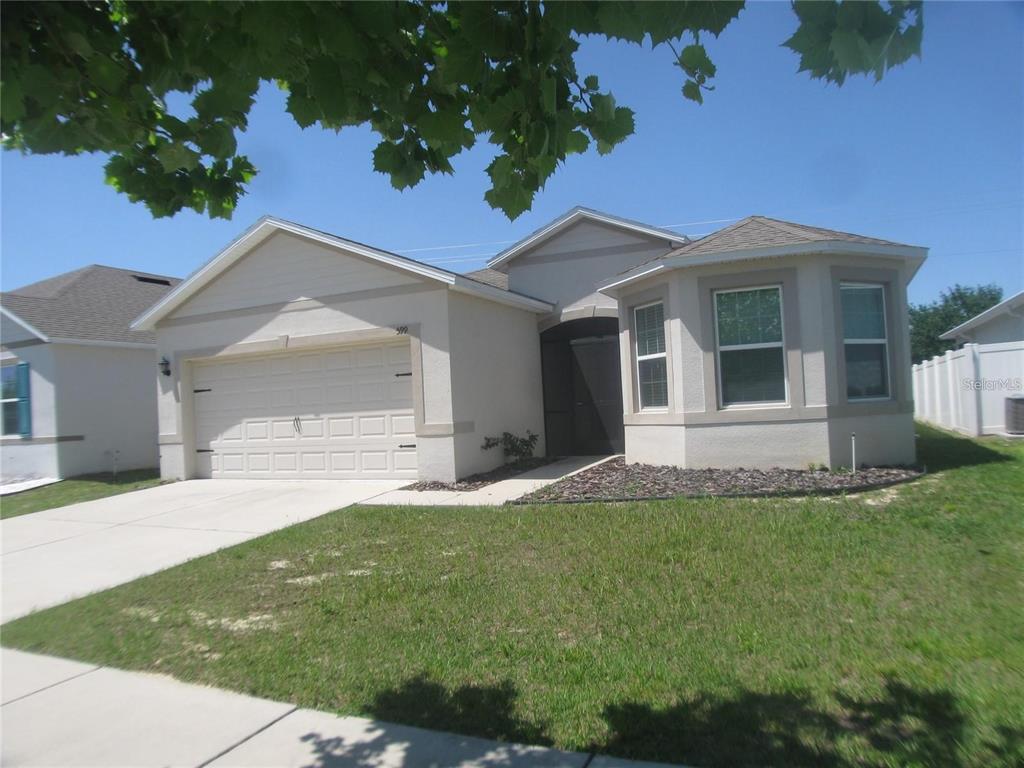 A single-story house with a beige stucco exterior, a two-car garage, and a bay window — 599 AUTUMN STREAM DRIVE, AUBURNDALE, FL