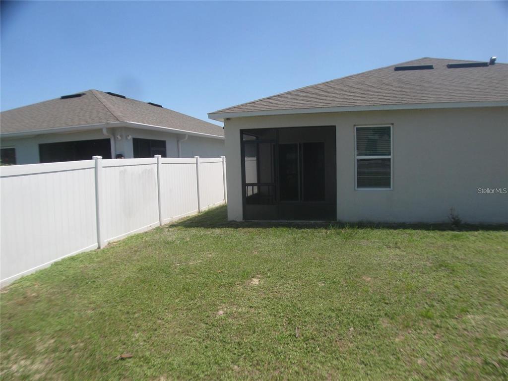 The exterior view shows a house with a screened-in porch and a white vinyl fence — 599 AUTUMN STREAM DRIVE, AUBURNDALE, FL