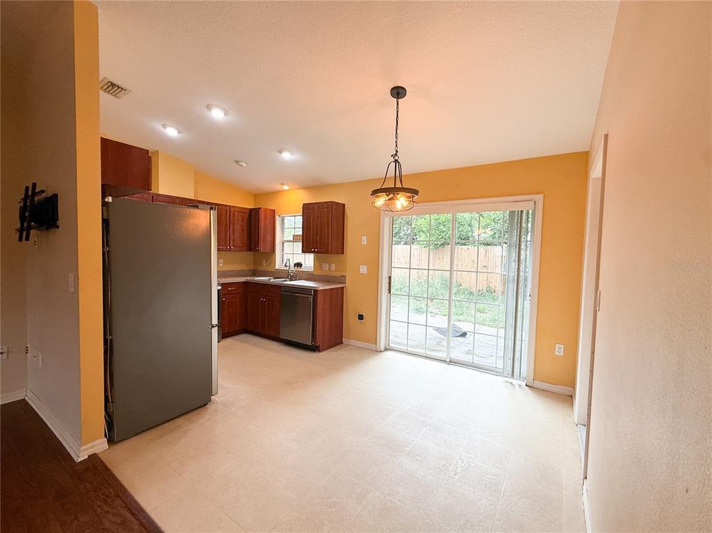 A kitchen with wood cabinets, stainless steel appliances, and a sliding glass door to outside — 11740 RANCHO DRIVE, LEESBURG, FL