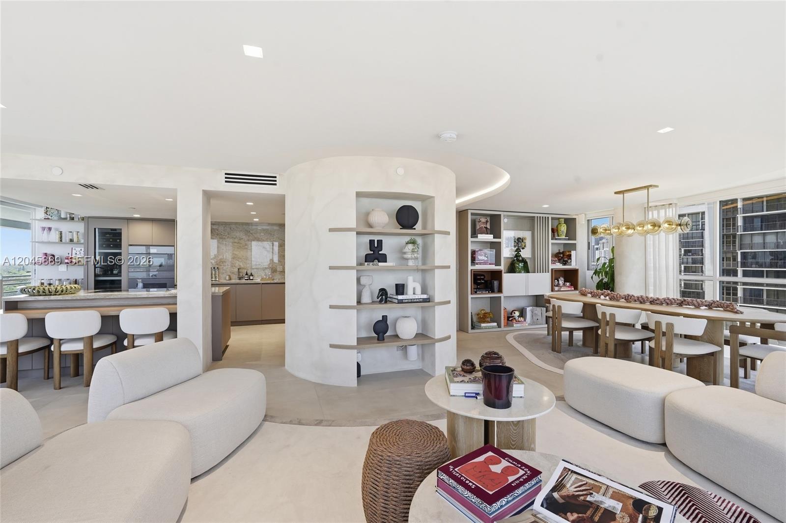 A modern, open-concept living and dining area features a curved, built-in display shelf — 2025 Brickell Ave # 1401, Miami FL 33129, MIAMI, FL