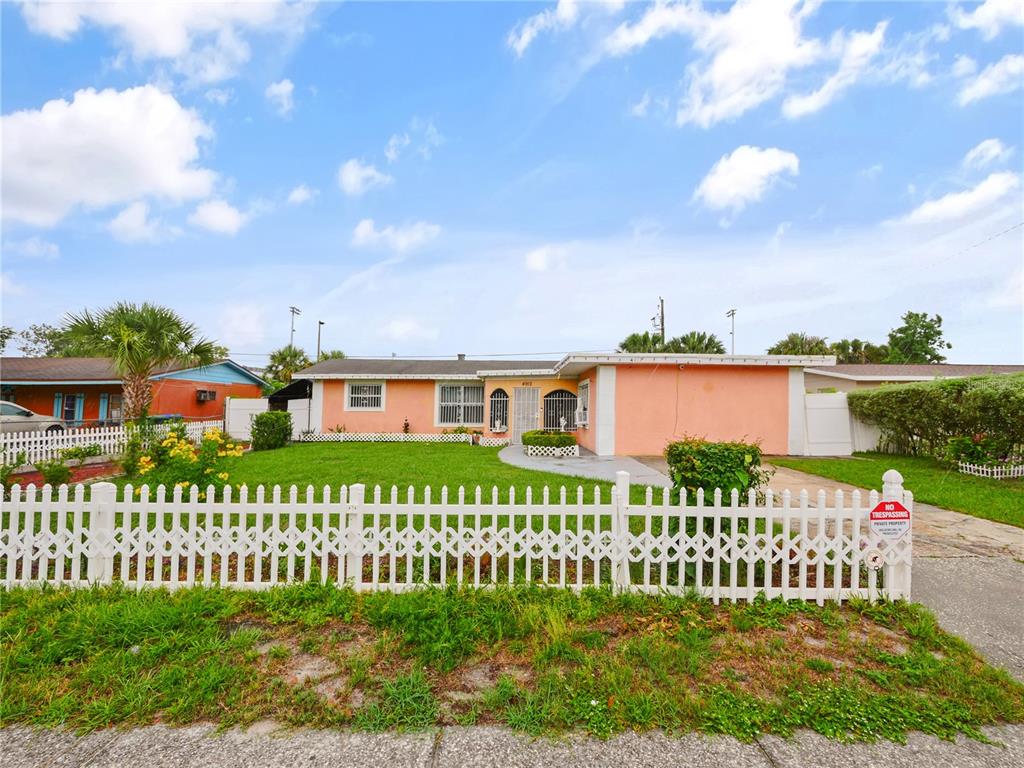 A single-story peach-colored house features a white picket fence and a grassy front yard — 4912 DANNY BOY CIRCLE, ORLANDO, FL