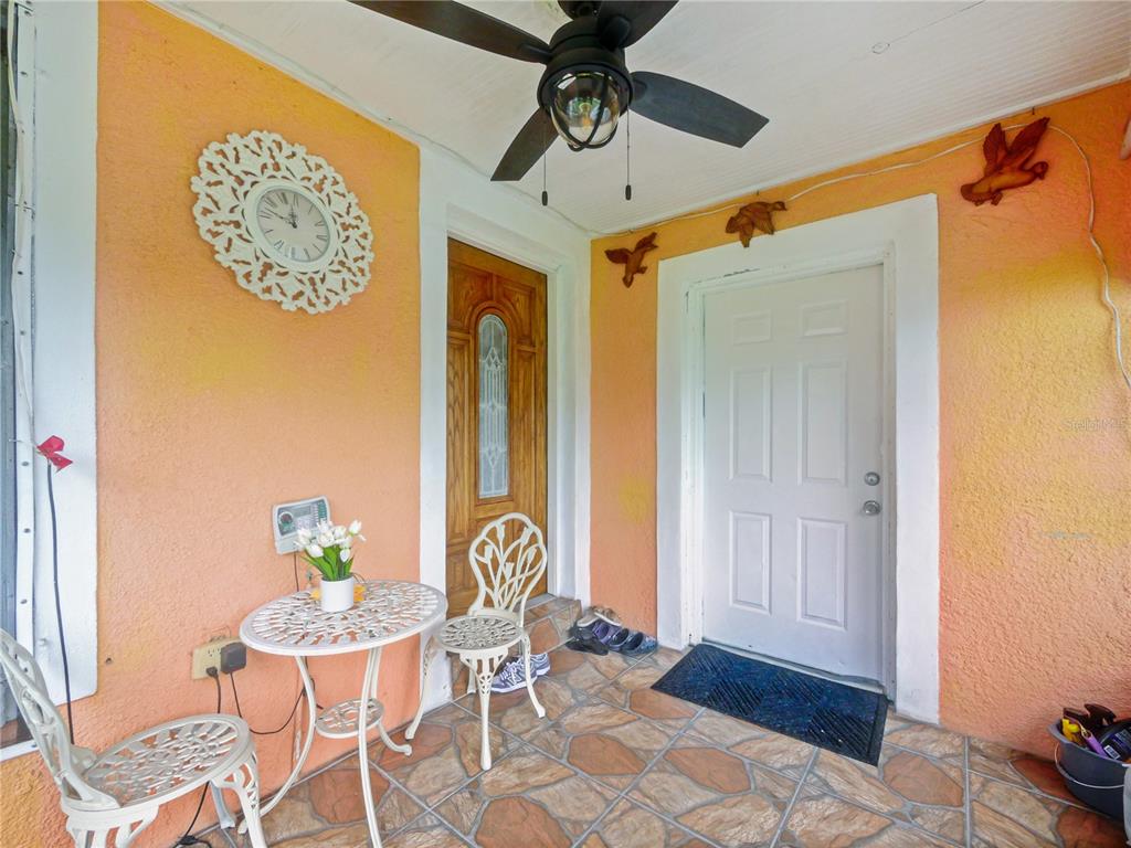 A covered porch features peach-colored walls, a tiled floor, a ceiling fan, and patio furniture — 4912 DANNY BOY CIRCLE, ORLANDO, FL