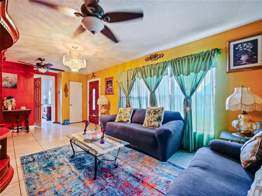 A living room features a blue sofa, a colorful area rug, and yellow walls — 4912 DANNY BOY CIRCLE, ORLANDO, FL